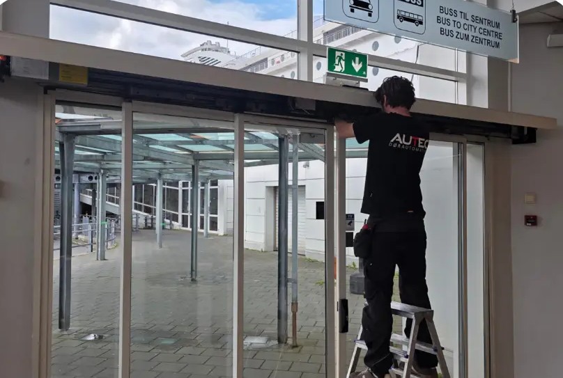 Chris installing an automatic sliding door system above a glass entrance